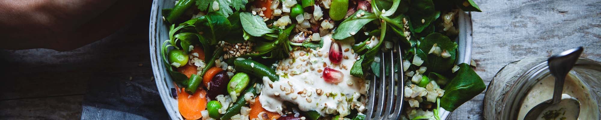 Bowl mit Blumenkohlreis, Salat und Granatapfelkernen