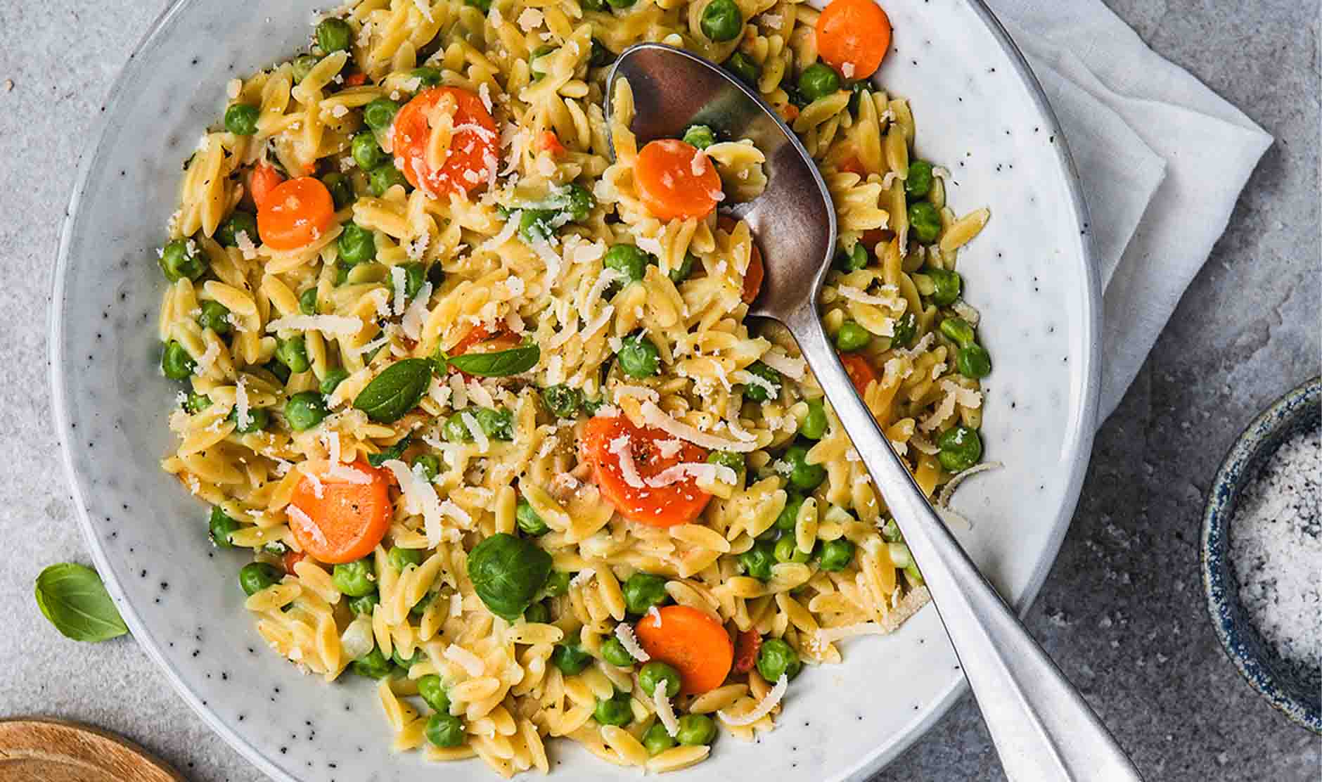 Auf einem Teller Orzotto mit Erbsen & Karotten Rahm