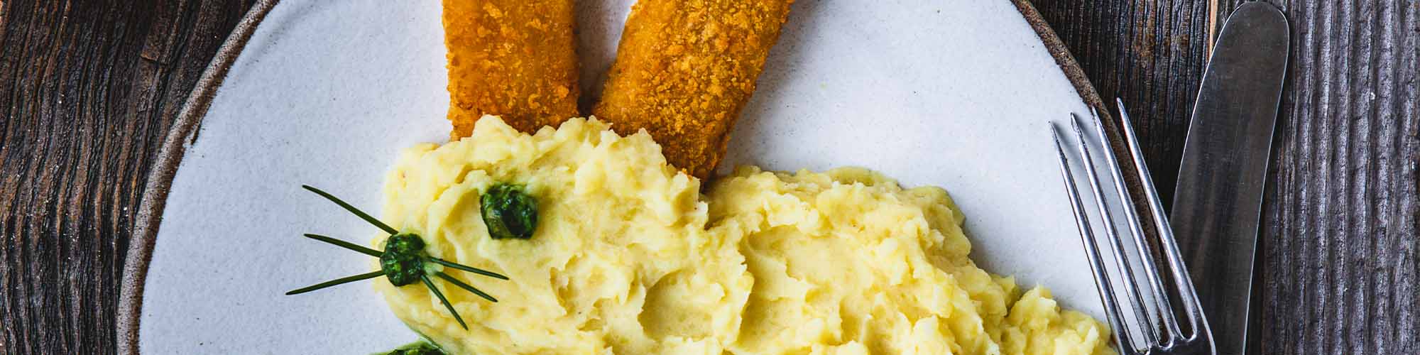 Fischstäbchen und Kartoffelbrei als Kaninchen angerichtet auf einem Teller