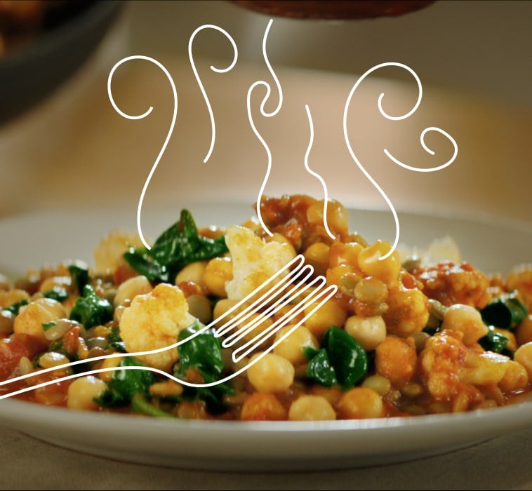 Ein Teller mit gekochten Kichererbsen, Blumenkohl und Spinat 